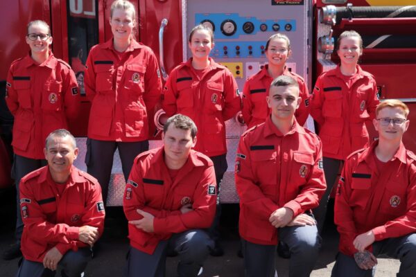 bombeiros voluntários em frente a um veículo de combate a incêndio