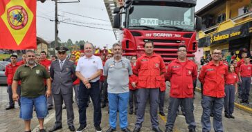 Bombeiros voluntários perfilados na frente da plataforma elevatória dos Bombeiros Voluntários de Joinville.